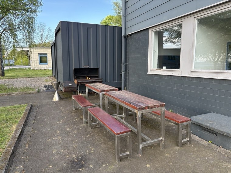 Außenbereich mit Grill, Bänken und Tischen am LAN-Bunker