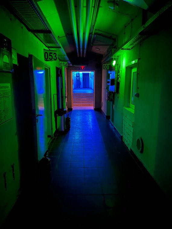 Grün beleuchteter Bunkergang mit Original-Raumnummern